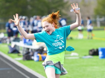 Girls on the Run participant jumps at 5K finish.